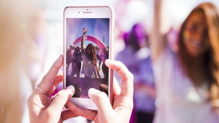Bild von Händen die mit einem iPhone ein Foto einer jungen Frau aufnehmen