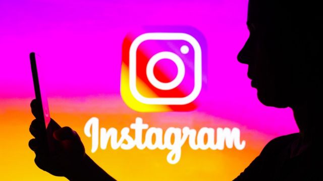Instagram Logo und die Silhouette eines Menschen, der auf sein Smartphone schaut