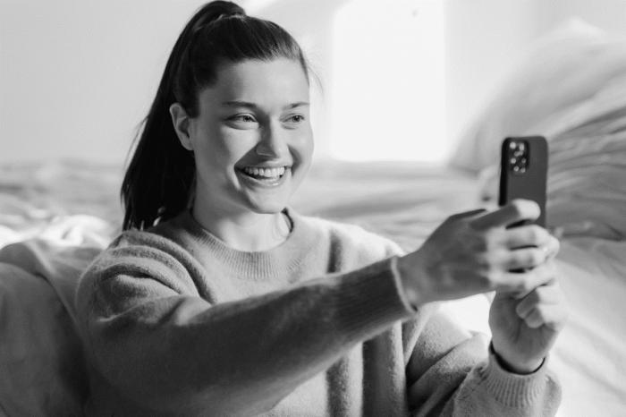 ein schwarz-weiß Foto einer jungen Frau, das ein Selfie von sich macht