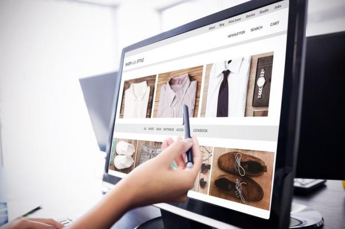 Computerbildschirm mit verschiedenen Produktbildern für E-Commerce und einer Hand mit Stift, die darauf zeigt