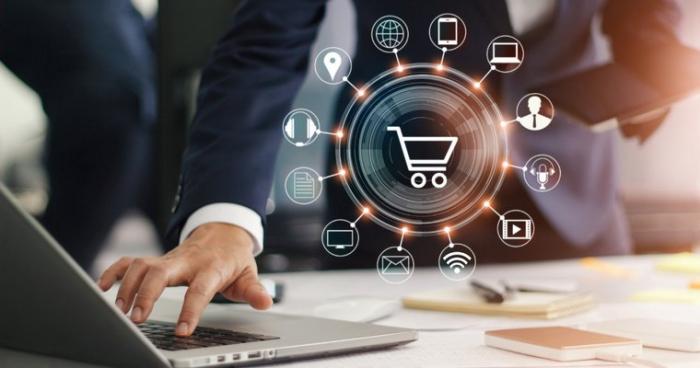 eine Grafik, die alle wichtigen Eckpunkte des E-Commerce anzeigt neben einer Hand, die einen Laptop nutzt