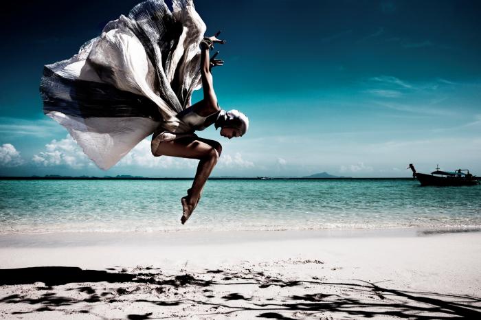 Modefotografie – ein Modell in einem Kick springt an einem Strand in die Luft