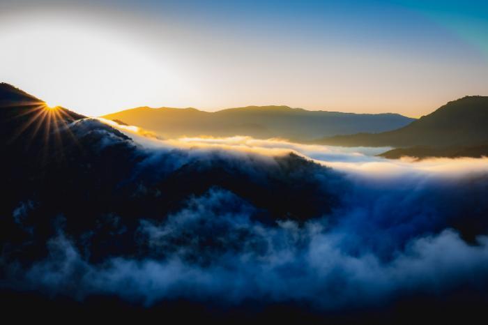 eine Berglandschaft in dessen Hintergrund die Sonne aufgeht