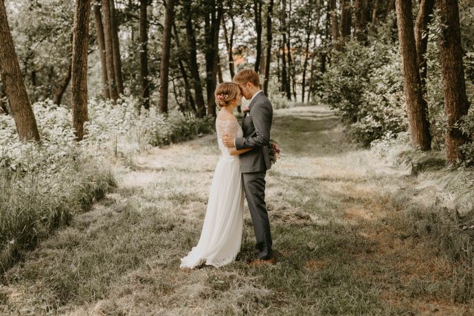 ein Hochzeitspaar küsst sich im Wald