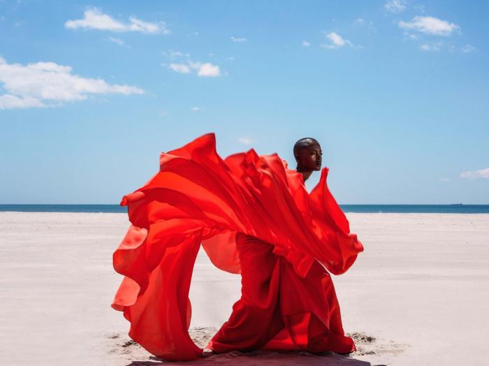 Frau mit wehendem roten Kleid am Strand