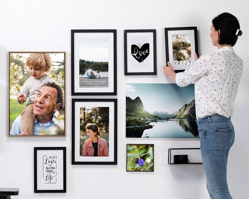 eine Frau hängt Bilder auf, die im DM Fotoparadies kreiert wurden